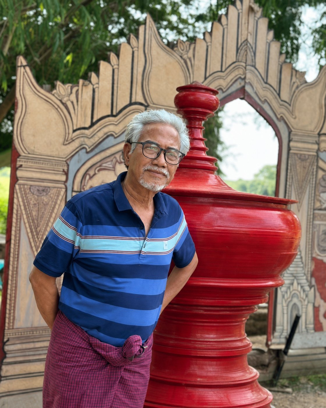 Tin Shwe Cho standing beside a traditional architectural structure